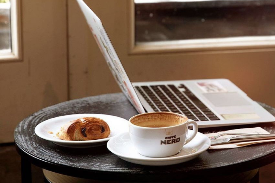 An image of Caffe Nero’s coffee and a croissant on a table inside the coffee shop