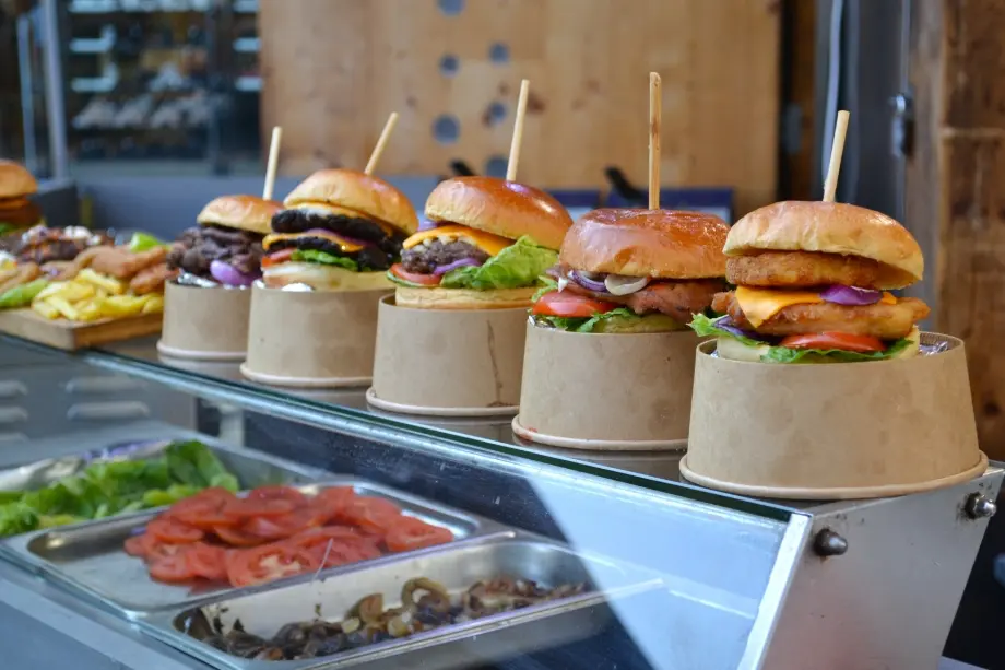 Line of homemade burgers of different varieties with tooth picks through the middle of each.