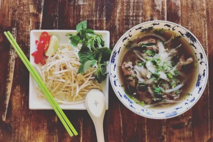 An image of a bowl of Vietnamese noodle soup with a side dish