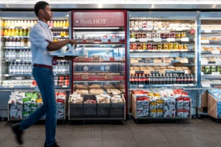 Full in store shelves with worked carrying someones order walking across the front.