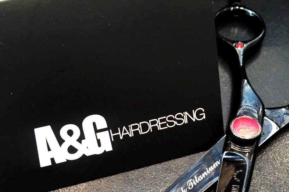 A close up of the A&G logo and a pair of hairdressing scissors