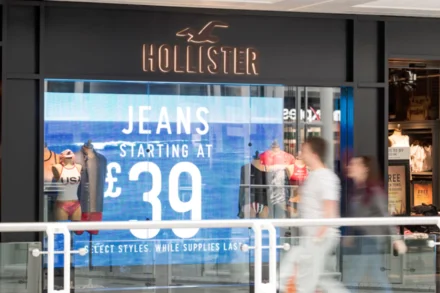 Shop front with Hollister logo and mannequins in the window.