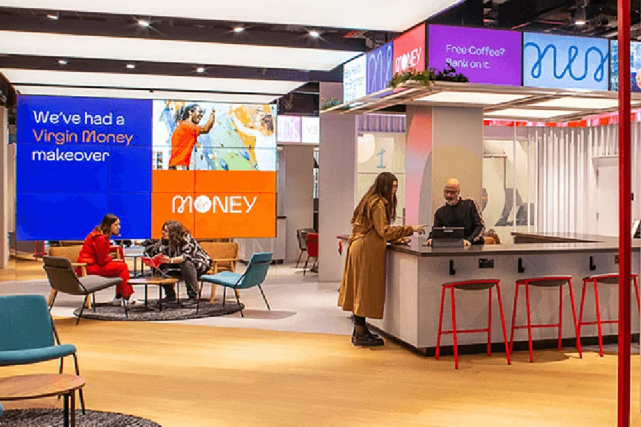 Store layout with tables and chairs and big screen with Virgin Money branding