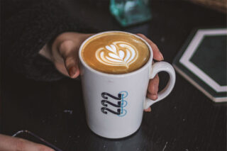 Hand holding coffee in triple two branded mug